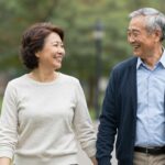 Para z dużą różnicą wieku spacerująca w parku, trzymająca się za ręce